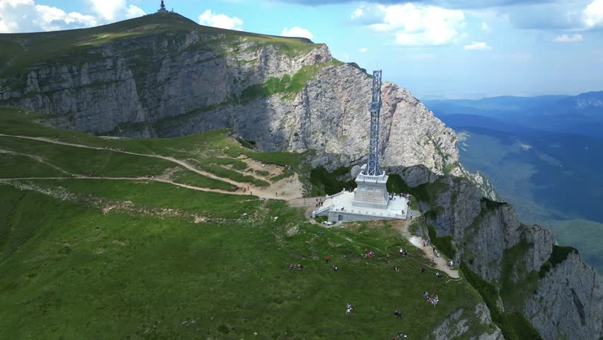 The Heroes Monument or Caraiman cross  metallic structure in memory of fallen war heroes  on the Bucegi Mountains plateau with Prahova Valley on the background Romania aerial drone view