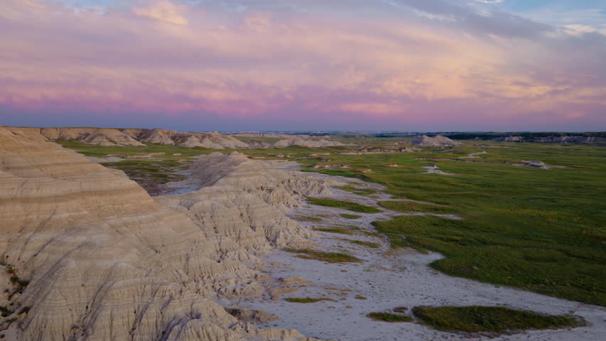 Rugged Badlands terrain is bathed in soft golden sunset light from above, revealing dramatic peaks, deep shadows, and the raw textures of this breathtaking natural landscape