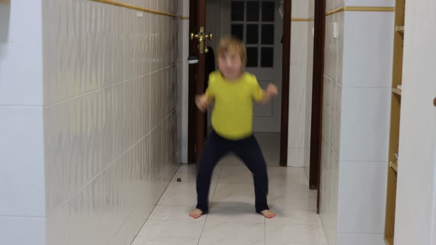 Energetic child dancing barefoot in corridor