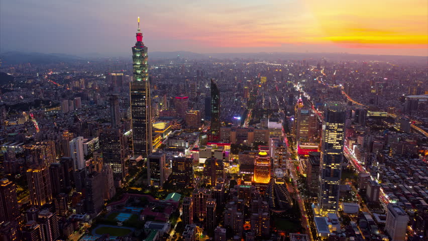 Aerial hyperlapse at sunset above Downtown Taipei, vibrant capital of Taiwan, where 101 Tower stands out amid modern skyscrapers in XinYi District and city lights dazzle under dramatic twilight sky