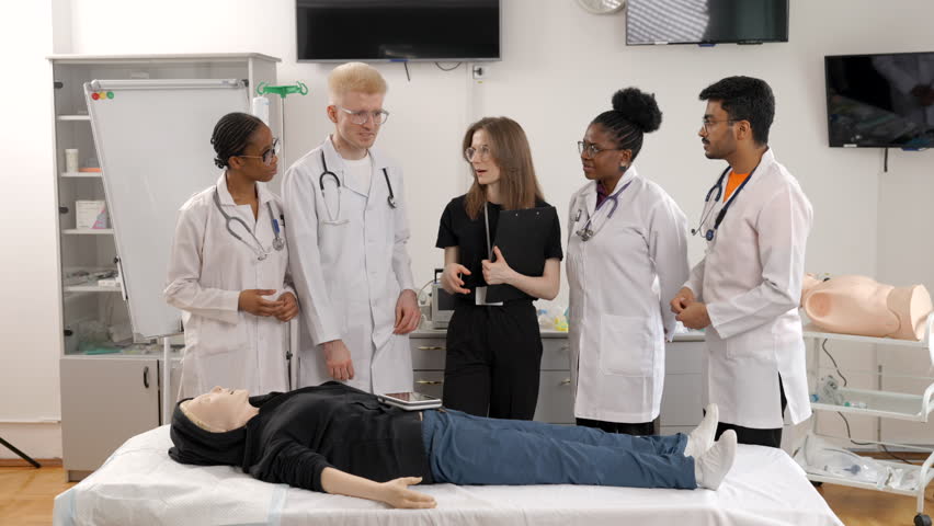 Group of doctors standing at the bed with mannequin at first aid training course