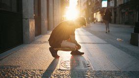 Athletic man crouching on city street at sunrise tying shoelaces. Symbol of preparation, discipline, and motivation before morning workout in urban lifestyle context - Powered by Shutterstock - Get 15% off with code: PIKWIZARD15