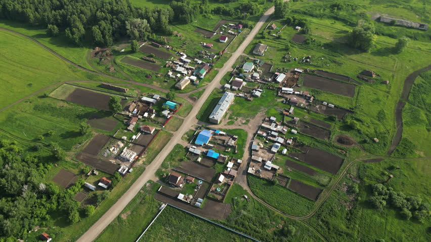 Rural landscape highlighting community development, verdant farmland spanning cultivated plots near residential structures amid lush natural scenery