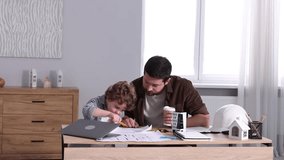 Choice of profession. Father and his son exploring engineering drawings at table indoors, camera moving in - Powered by Shutterstock - Get 15% off with code: PIKWIZARD15