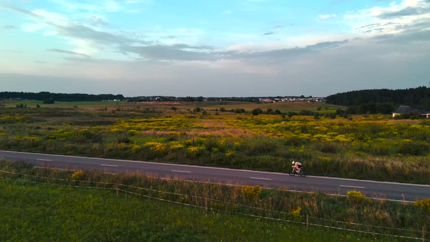 Drone shot of a cyclist on a road bike at sunset, symbolizing endurance, speed, and healthy active lifestyle.