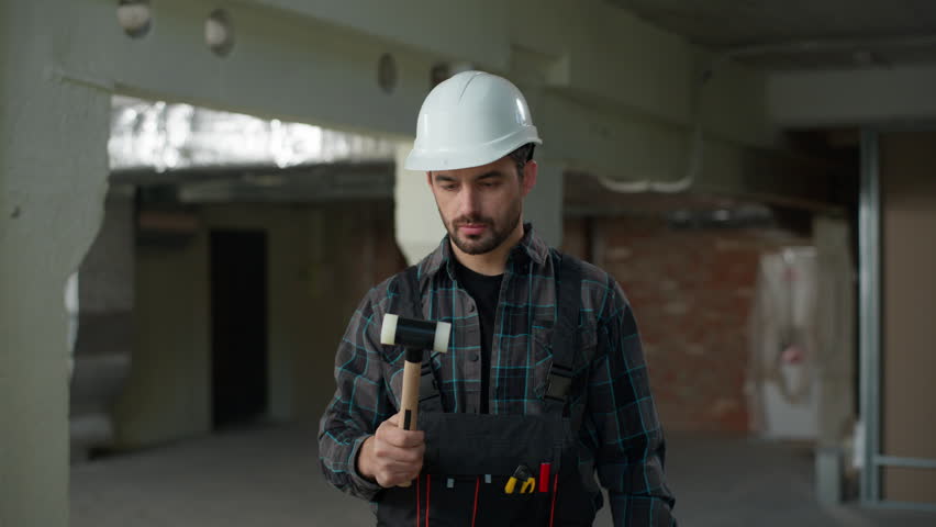 Caucasian man builder engineer in hard hat holding hammer check tool beat helmet safety on construction site building protection architect foreman repair work industrial handyman looking at camera
