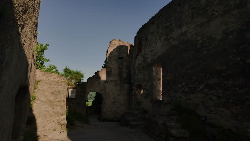 Video moving from medieval castle ruins to a scenic panorama of Dürnstein town, green hills and vineyard valleys in Austria’s Wachau region. Historic and picturesque view.