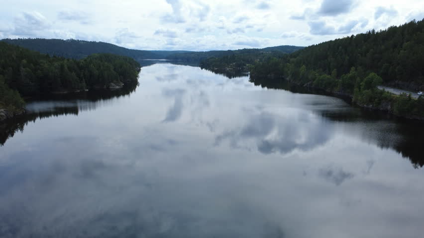 Aerial Drone Flight Over Reflective Lake in Norway with Trees and Clouds