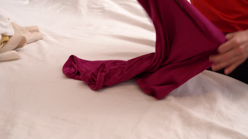 Young woman folds t-shirts neatly during home cleaning. The video shows organized lifestyle, tidying process, and minimalism at home, perfect for household, lifestyle, or productivity content.