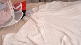 A young woman takes clothes out of a laundry basket at home, preparing to sort them before washing. The scene illustrates everyday chores, home organization, and household lifestyle - Powered by Shutterstock - Get 15% off with code: PIKWIZARD15