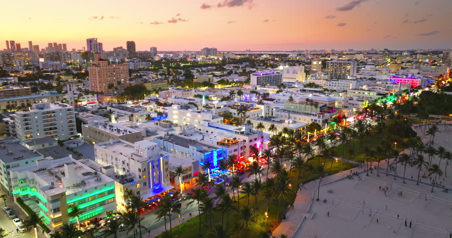 Art Deco buildings lit up along Ocean Drive in Miami Beach. Lively evening atmosphere in tourist hotspot.