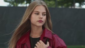 Close-up portrait of young woman with calm and confident expression outdoors. Natural look, minimal makeup, long hair, and soft urban background. - Powered by Shutterstock - Get 15% off with code: PIKWIZARD15
