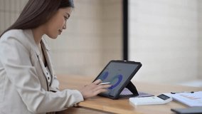 Businesswoman analyzing financial charts and data on a digital tablet, working efficiently in modern office - Powered by Shutterstock - Get 15% off with code: PIKWIZARD15