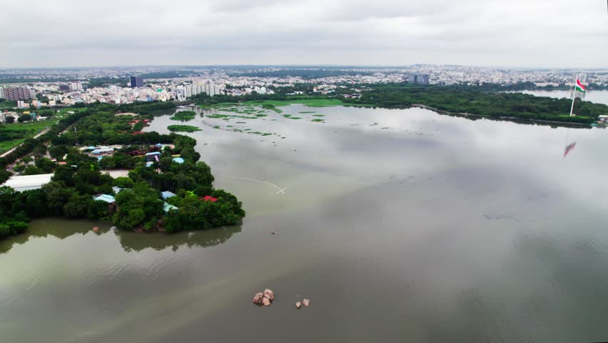 Hussain sagar lake with sky, moving train, and green city at hyderabad. day time, semi orbit shot, drone shot, 4k.