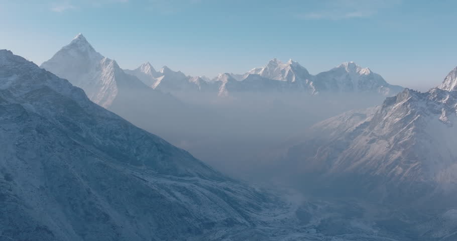 Aerial drone view of Everest Base Camp trek in Khumbu, Nepal. Morning snowfall and sunlight radiate spiritual energy across Ama Dablam and majestic Himalayan ranges under a dreamy clear blue sky