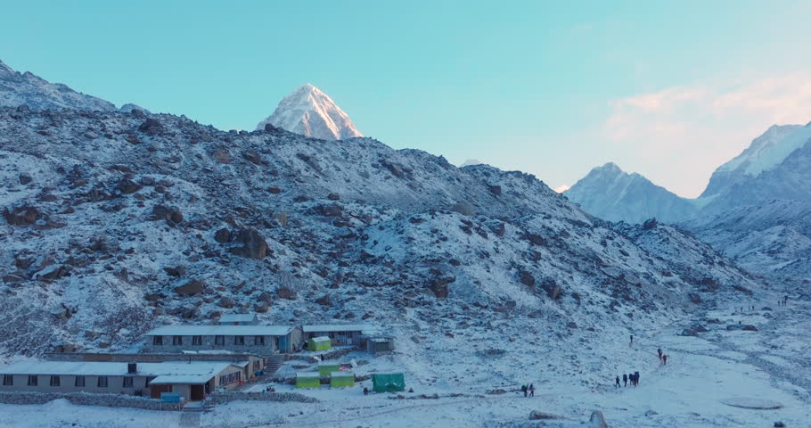 Aerial reveal drone shot of Everest Base Camp trek in Khumbu, Nepal. Morning snowfall uncovers Mount Pumori, Lobuche, and Nuptse as sunrise reflects on the Himalayas, creating a majestic travel scene