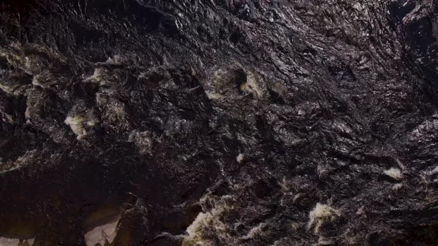 Top view down over the dark water of the Gatineau river as it flows into the rapids.