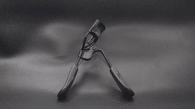 High-quality, cinematic close-up of a black eyelash curler on a dark, studio background. Perfect for beauty tutorials, cosmetic product advertising, and social media content. Use this modern footage  - Powered by Shutterstock - Get 15% off with code: PIKWIZARD15