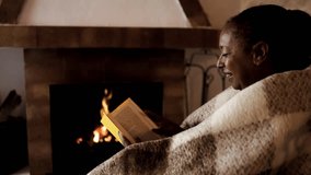 Senior African woman reading book by fireplace in cozy home - Retirement and lifestyle concept - Powered by Shutterstock - Get 15% off with code: PIKWIZARD15