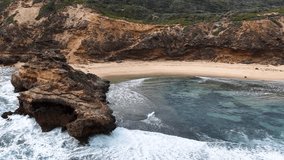 Sweeping aerial view of rocky coastline, turquoise water, and sandy beach under soft daylight - Powered by Shutterstock - Get 15% off with code: PIKWIZARD15