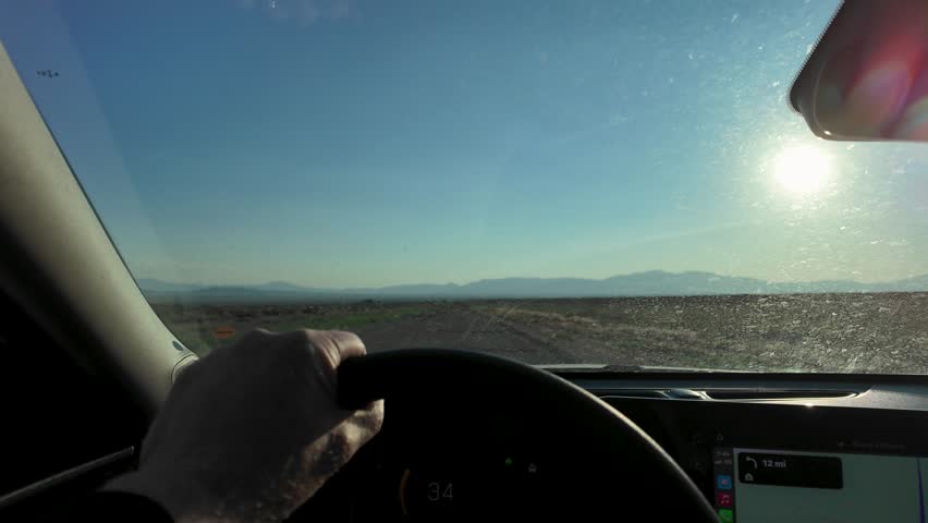 Interior View Of A Driver Driving A Car Through A Desert Landscape In Utah, USA.