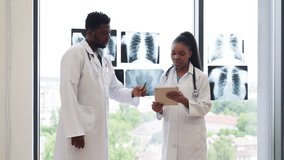 Two medical professionals, male and female, standing in clinic near window discussing x-rays, radiating professionalism and teamwork, symbolizing health care, dedication, expertise. - Powered by Shutterstock - Get 15% off with code: PIKWIZARD15