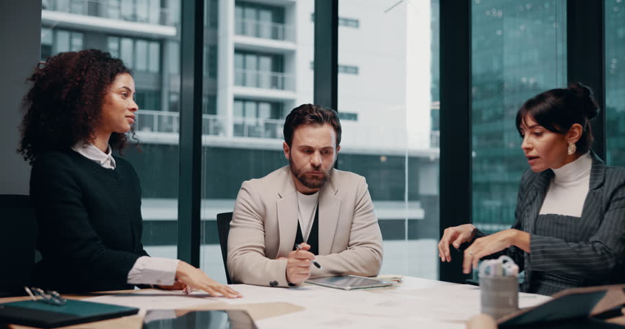 Business people, discussion and stress at meeting with architect for property development company. Man, women and ignore insight with blueprint, review or frustrated for real estate project at office