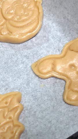 Festive holiday cookie dough lying on baking paper, showcasing traditional christmas baking preparation with various shapes ready for oven baking