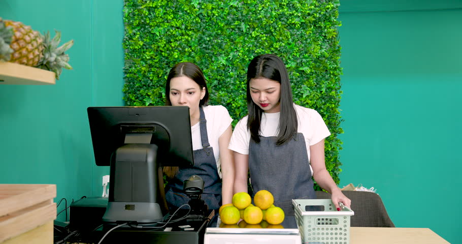 Asian LGBTQ owner hugging Caucasian partner while standing behind fruit counter smiling together before opening tropical grocery shop small business