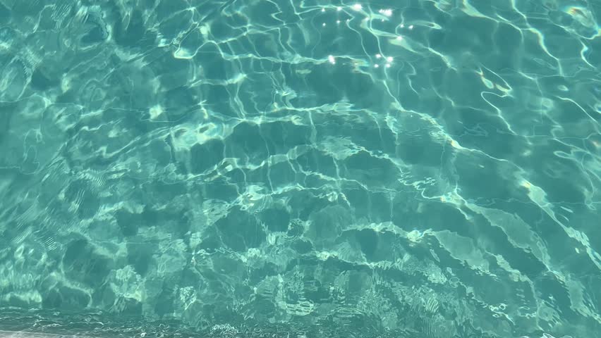 Top view of clear blue swimming pool water with sun reflections and soft ripples. Refreshing and relaxing summer scene, perfect for wellness, spa, or vacation themes.