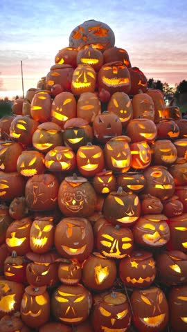 A lot of glowing carved pumpkins with spooky faces lit by candles at night. Traditional jack o lantern display for Halloween holiday, seasonal decoration at the annual Halloween Fair.
