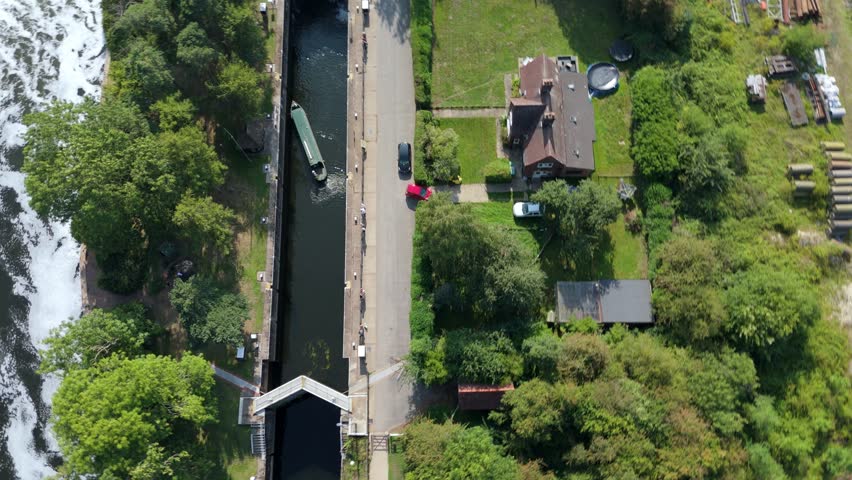 top down aerial drone footage of canal boat entering lock system at Gunthorpe Weir in Nottingham England sunny evening