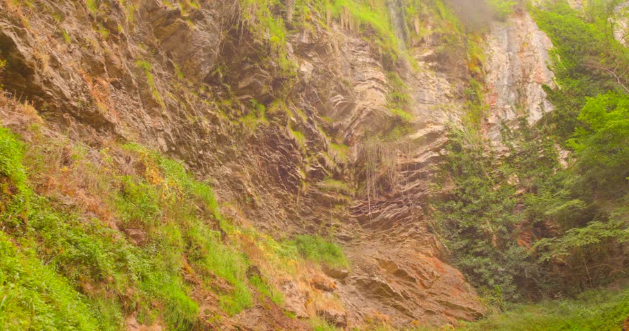 Cliff view of Alzen waterfall in Ariege, France, with visible rock layers and minimal water flow.