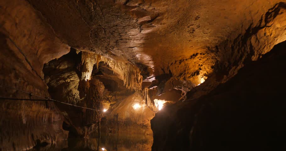 Journey through a beautifully lit cave showcasing dramatic rock formations and stalactites.