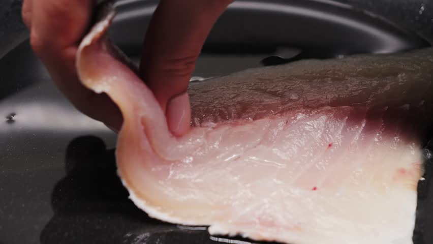 Preparing fresh fish fillet in a hot pan with oil to make a delicious meal, close-up of white fish fillet. High quality 4k footage