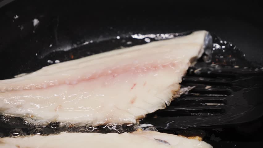 Preparing fresh fish fillet in a hot pan with oil to make a delicious meal, close-up of white fish fillet. High quality 4k footage
