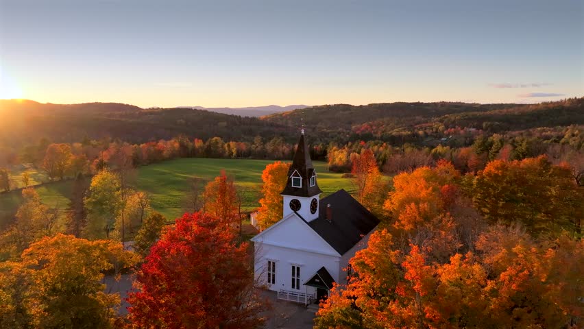 Aerial view of a white church surrounded by trees in autumn colors, with a green field in the background, Sugar Hill, New Hampshire, United States.