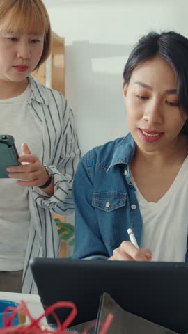 Vertical Screen : Young Asia businesswomen meeting check product purchase order on stock and save to tablet computer work at home office. Small business owner, online market delivery concept.