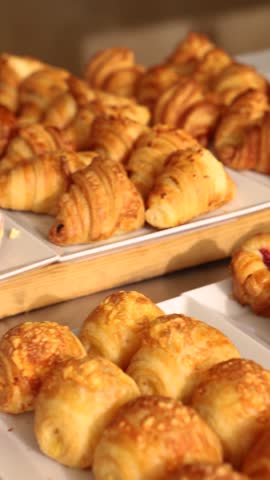 Variety of freshly baked pastry puff croissants and buns on display at buffet table in restaurant or hotel for breakfast or brunch. Morning meal concept for food blog and catering