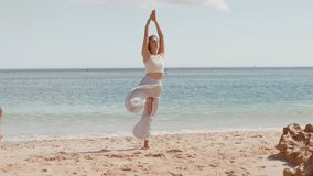 Young woman practicing Tree Pose on sandy beach near ocean balancing on one leg with hands in prayer position. Embracing stability, focus and mindfulness in peaceful, natural setting - Powered by Shutterstock - Get 15% off with code: PIKWIZARD15