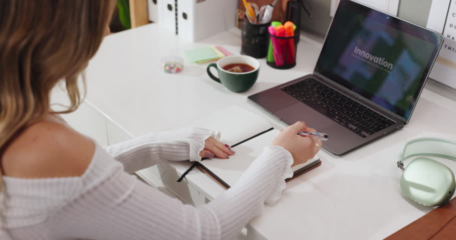 Woman, writing and notes with laptop at house for planning, creative ideas and innovation reminder. Back, female person and screen with notebook, research and project information for launch schedule