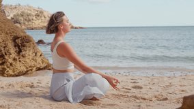Young woman practicing Gomukhasana Cow Face Pose on sandy beach stretching arms behind back promoting flexibility, wellness and relaxation with ocean view - Powered by Shutterstock - Get 15% off with code: PIKWIZARD15