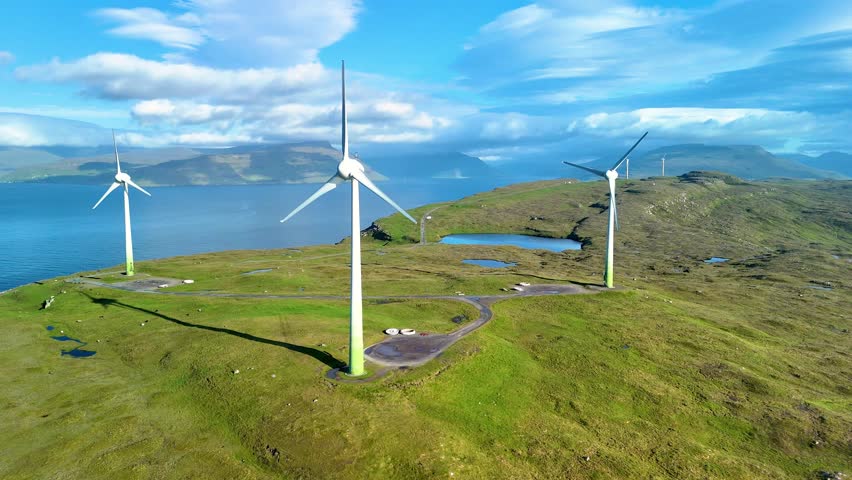 Discover the striking landscape of the Faroe Islands featuring towering wind turbines set against a backdrop of serene waters and lush greenery. huge windmills green energy transition