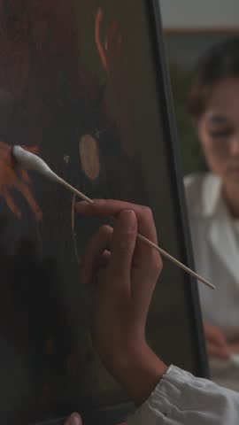 Painting conservator working in the laboratory, she is cleaning a Caravaggio oil painting using a cotton swab, art conservation concept