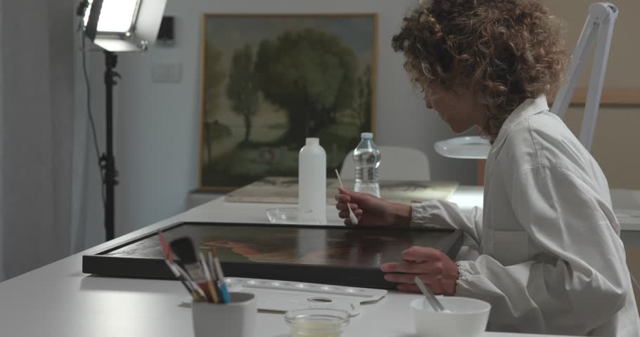 Painting conservators working together in the laboratory and restoring an oil painting, cultural heritage concept