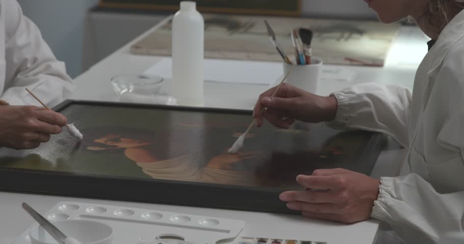 Painting conservators working in the laboratory, they are restoring a famous artwork using a cotton swab, cultural heritage concept