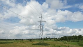 High-voltage electricity transmission tower standing against lush landscape. Steel infrastructure silhouetted beneath cloudy summer sky with expansive green field surrounding metal structure - Powered by Shutterstock - Get 15% off with code: PIKWIZARD15