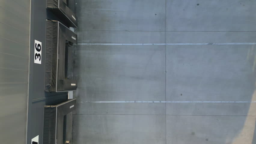 Aerial view of a distribution warehouse with loading docks and parked trucks, showcasing efficient freight logistics and organized cargo handling.