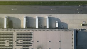 Aerial drone footage of a modern distribution warehouse with loading docks and parked trucks, showcasing efficient freight logistics and streamlined cargo handling. - Powered by Shutterstock - Get 15% off with code: PIKWIZARD15