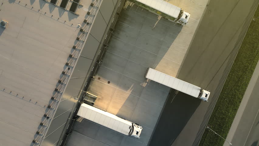 Aerial view of a logistics hub with three trucks at loading docks, showcasing efficient freight transportation in a modern warehouse setting. - Powered by Shutterstock - Get 15% off with code: PIKWIZARD15